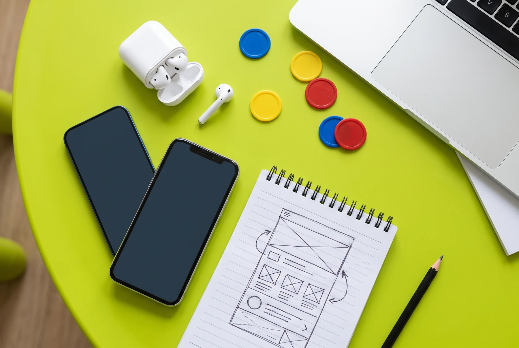 Phones and a hand-drawn mobile interface sketch on lime desk